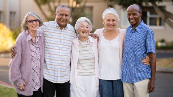 Portrait of cheerful senior people standing with arms around each other