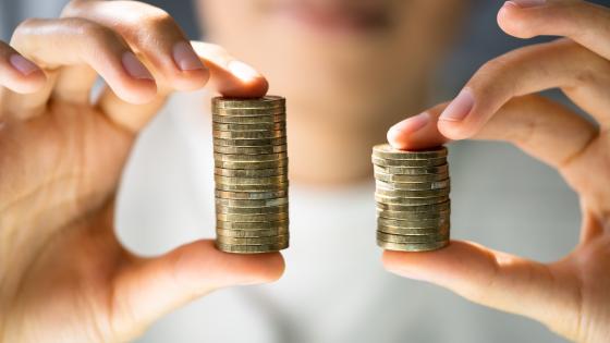 Person holding two different sized stacks of coins