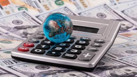 Glass miniature globe against a background of US dollar bills