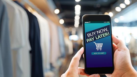 man holding mobile phone with "buy now pay later" on display